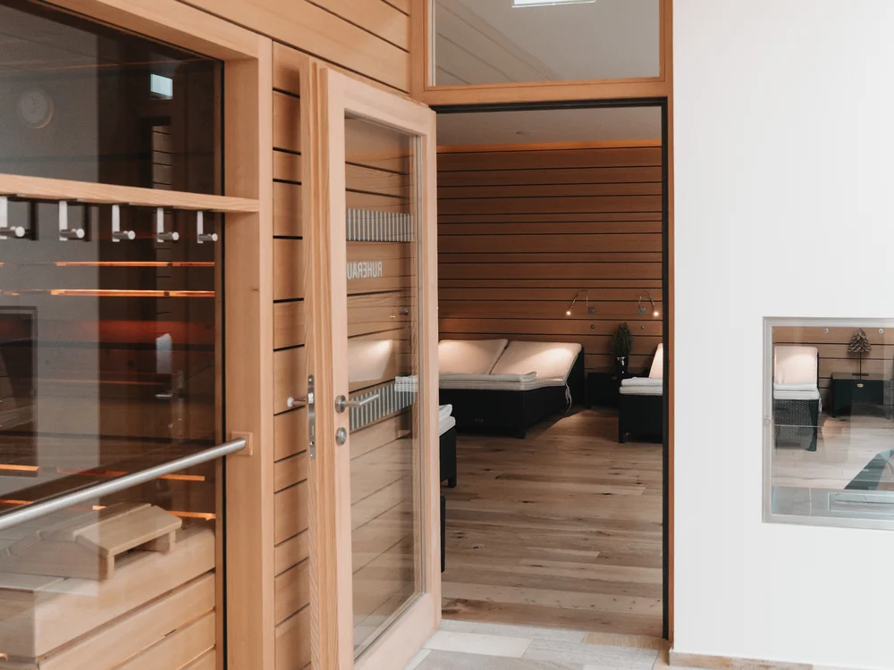 Wooden sauna with glass door and adjoining relaxation room