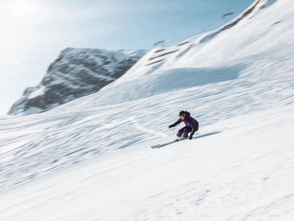 Ihre Auszeit in Lech am Arlberg Skifahrer fährt eine verschneite Bergflanke hinunter