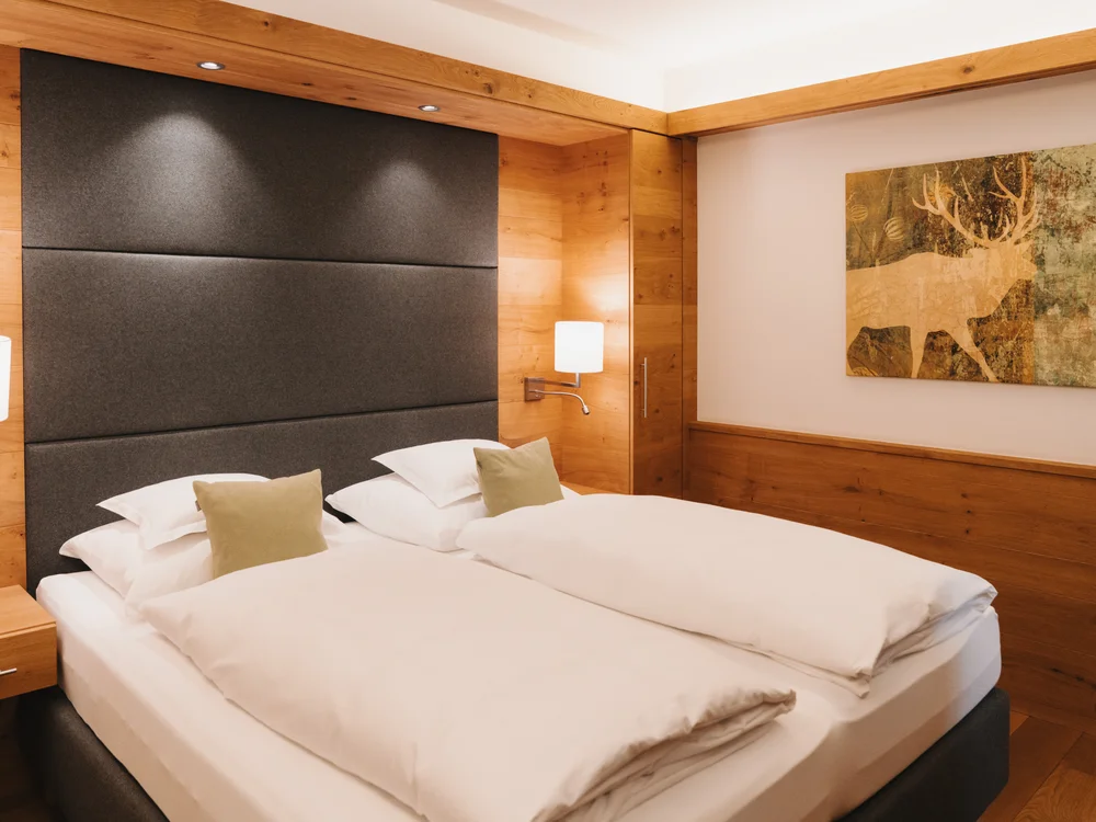 Ihre Auszeit in Lech am Arlberg Hotelzimmer mit zwei Einzelbetten, Holzvertäfelung und Hirschbild an der Wand