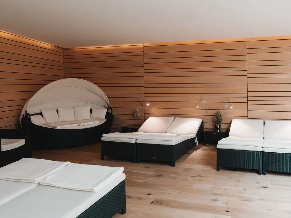 Ihre Auszeit in Lech am Arlberg Ruheraum mit weißen Liegen und rundem Daybed vor holzverkleideten Wänden