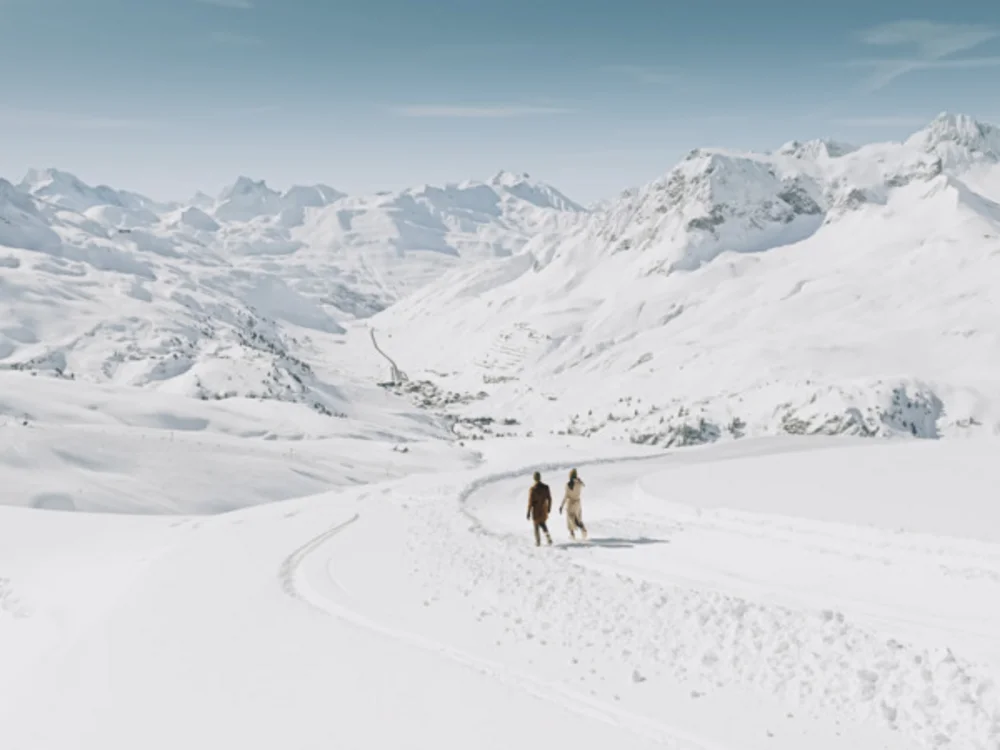 Ihre Auszeit in Lech am Arlberg Zwei Menschen wandern durch eine verschneite Berglandschaft
