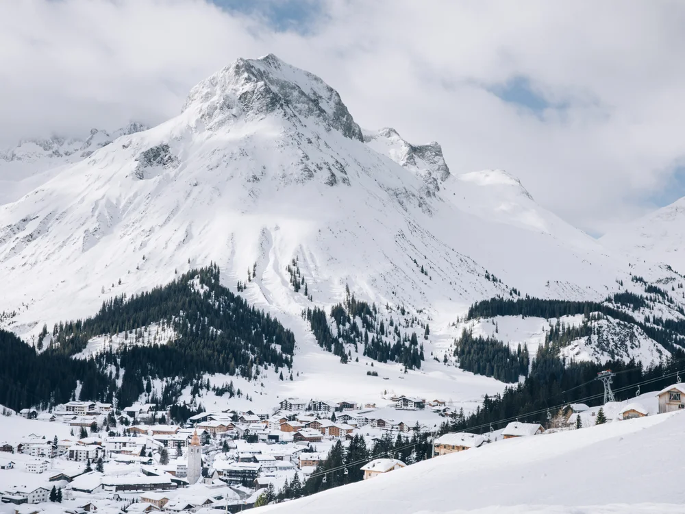 Ihre Auszeit in Lech am Arlberg Verschneites Bergdorf unter einem hohen, schneebedeckten Gipfel