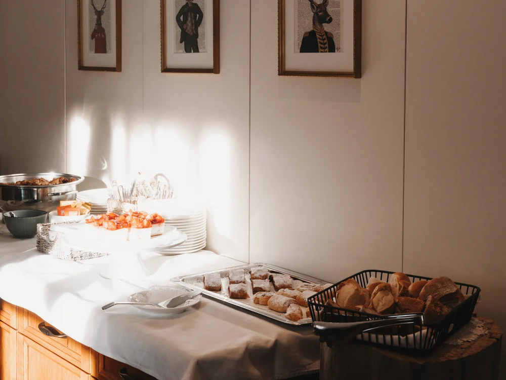 Ihre Auszeit in Lech am Arlberg Frühstücksbuffet mit Brot, Gebäck, Obst und gerahmten Hirschbildern