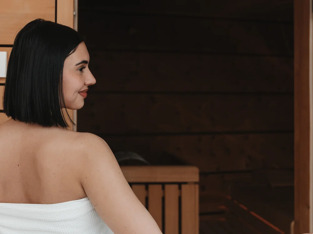 Ihre Auszeit in Lech am Arlberg Frau im weißen Handtuch vor einer Holzsauna