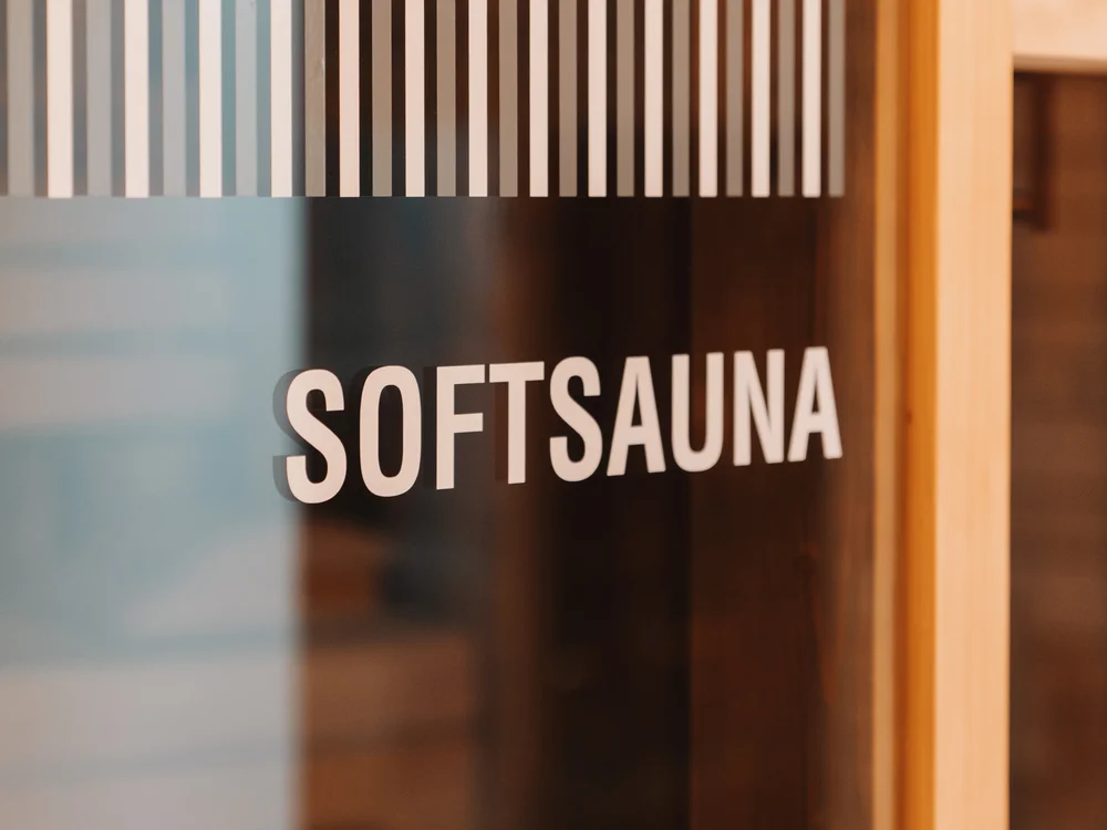 Ihre Auszeit in Lech am Arlberg Glastür mit der Aufschrift Softsauna und hellem Holzrahmen