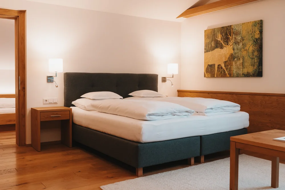Helles Schlafzimmer mit Doppelbett, Holzboden, Nachttischlampen und Wandbild
