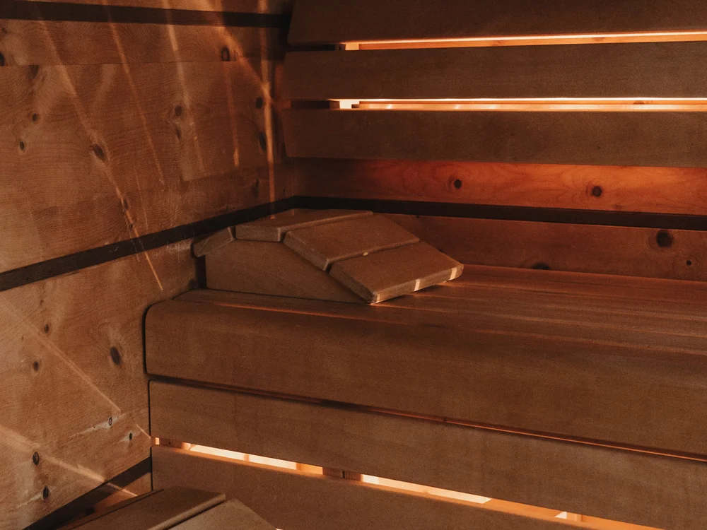 Ihre Auszeit in Lech am Arlberg Innenraum einer Holzsauna mit Sitzbänken und warmem Licht