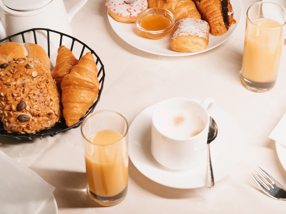 Ihre Auszeit in Lech am Arlberg Frühstückstisch mit Gebäck, Kaffee, Orangensaft und verschiedenen Speisen