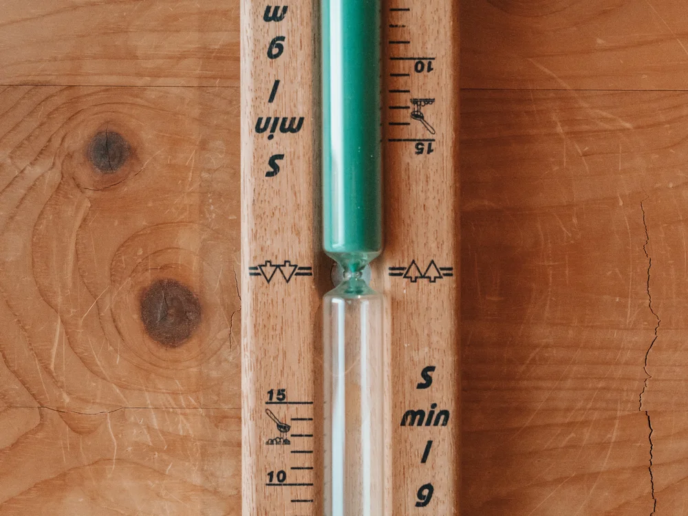 Ihre Auszeit in Lech am Arlberg Sanduhr mit grüner Füllung an einer Holzvertäfelung