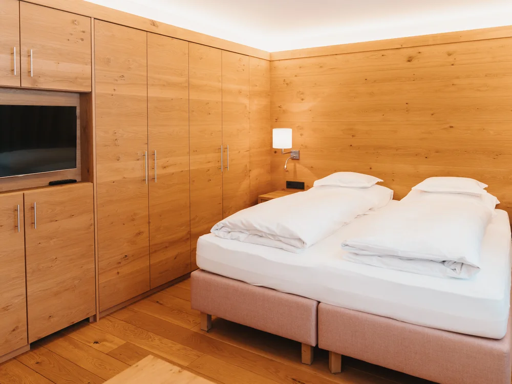Ihre Auszeit in Lech am Arlberg Hotelzimmer mit Doppelbett, heller Holzeinrichtung und Fernseher