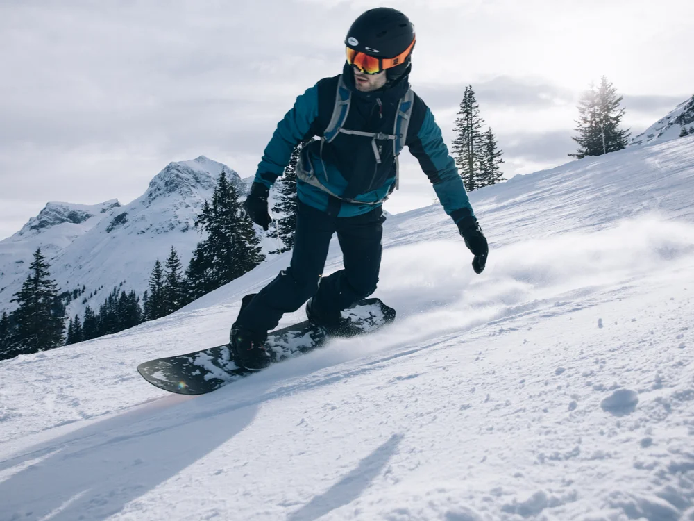 Ihre Auszeit in Lech am Arlberg Snowboarder fährt über einen verschneiten Hang vor einer Bergkulisse