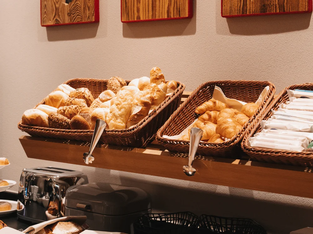 Ihre Auszeit in Lech am Arlberg Brot- und Gebäckkörbe an einem Buffet mit dekorativen Holztafeln
