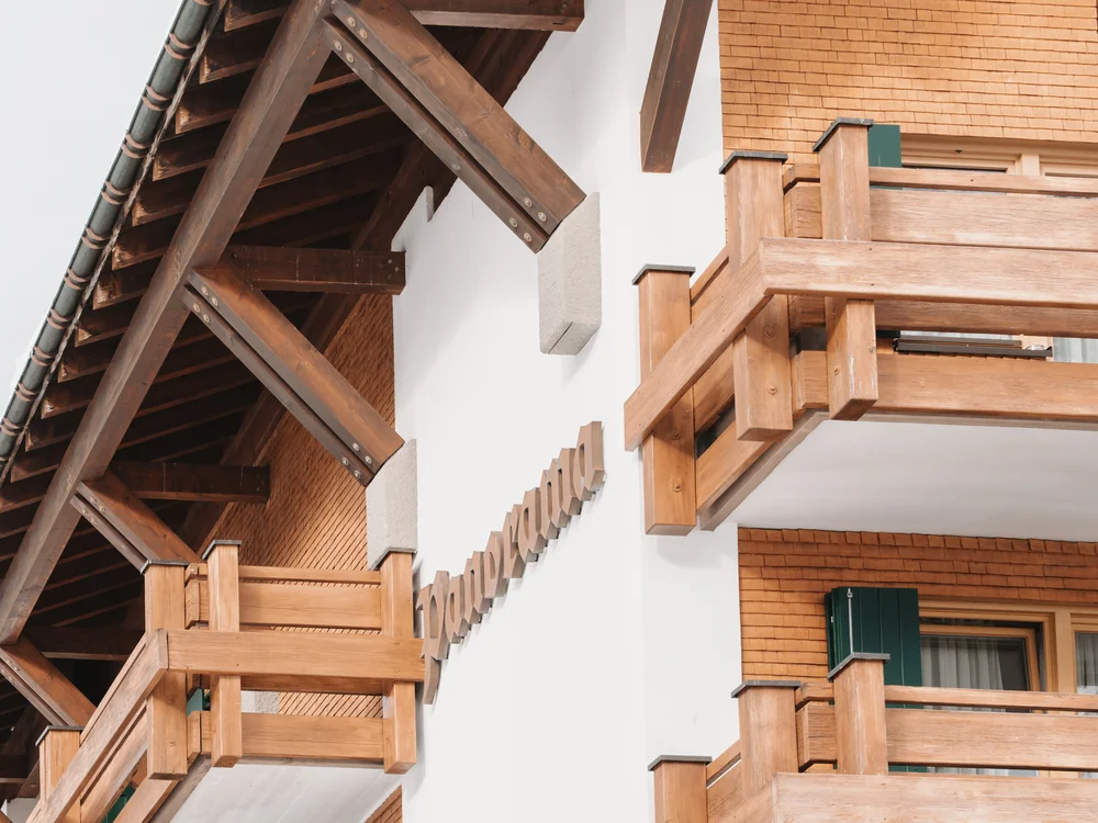 Ihre Auszeit in Lech am Arlberg Holzbalkone und Dachkonstruktion an einem Gebäude mit Schindelfassade