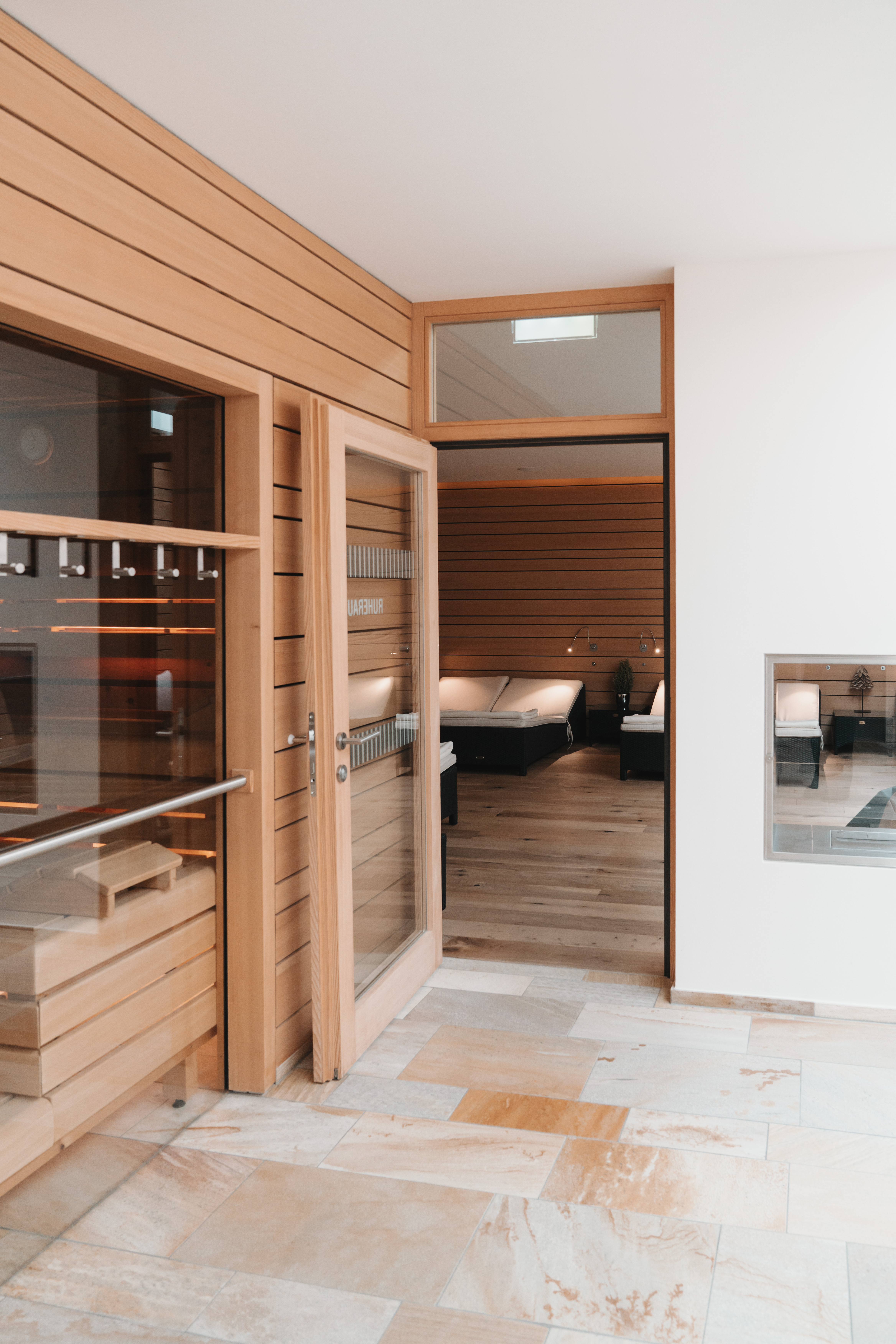 Ihre Auszeit in Lech am Arlberg Holzsauna mit Glastür und angrenzendem Ruheraum